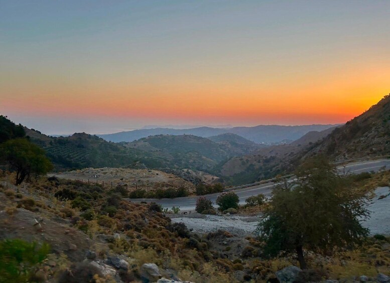 A mountainous landscape during sunset with a winding road. 5
