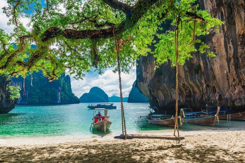 A beach with boats, clear water, and limestone cliffs. 2
