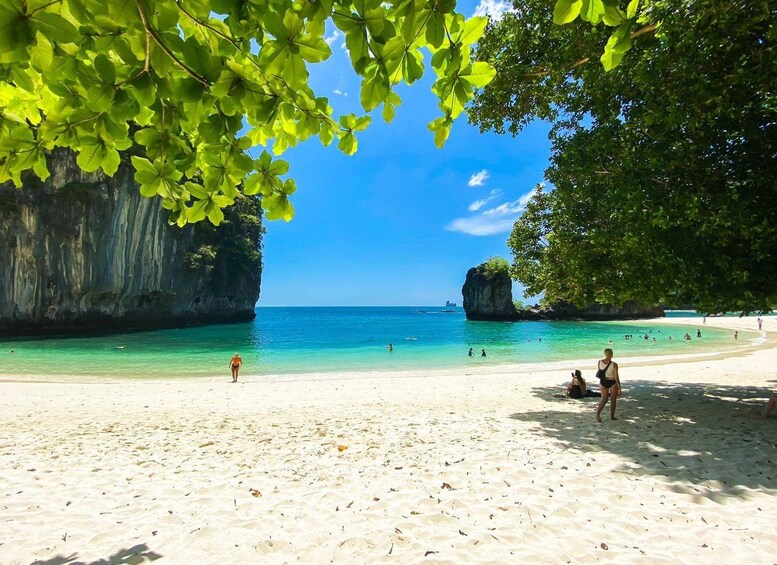 A beach with clear turquoise water, white sand, and lush green foliage. 5