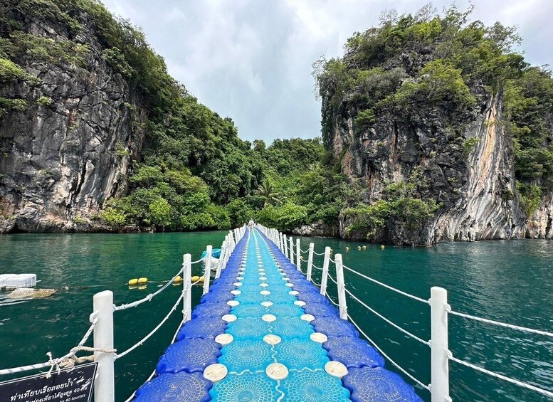 A blue bridge with white railings leading through a narrow water channel surrounded by steep cliffs. 5