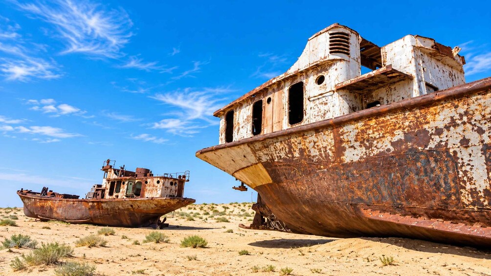 Two rusted, abandoned ships in a desert landscape. 2