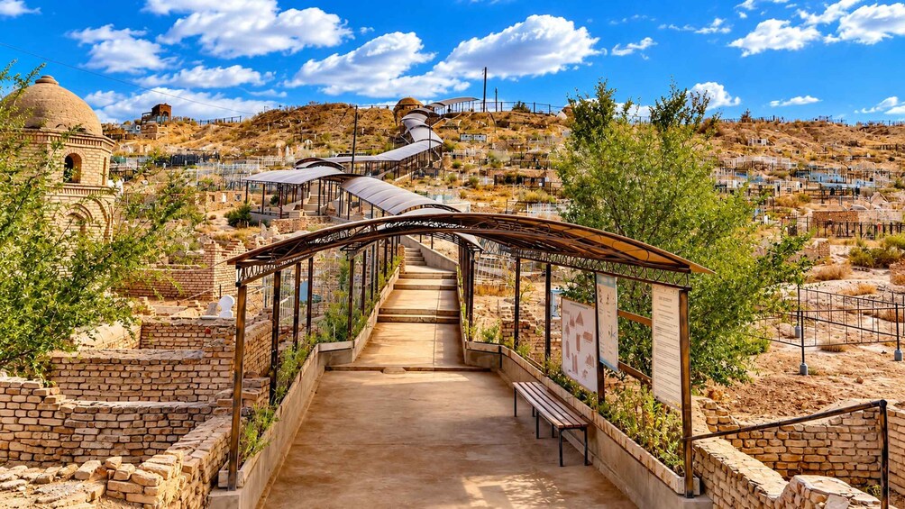 A pathway leading through an archaeological site with ancient structures and a clear sky. 5