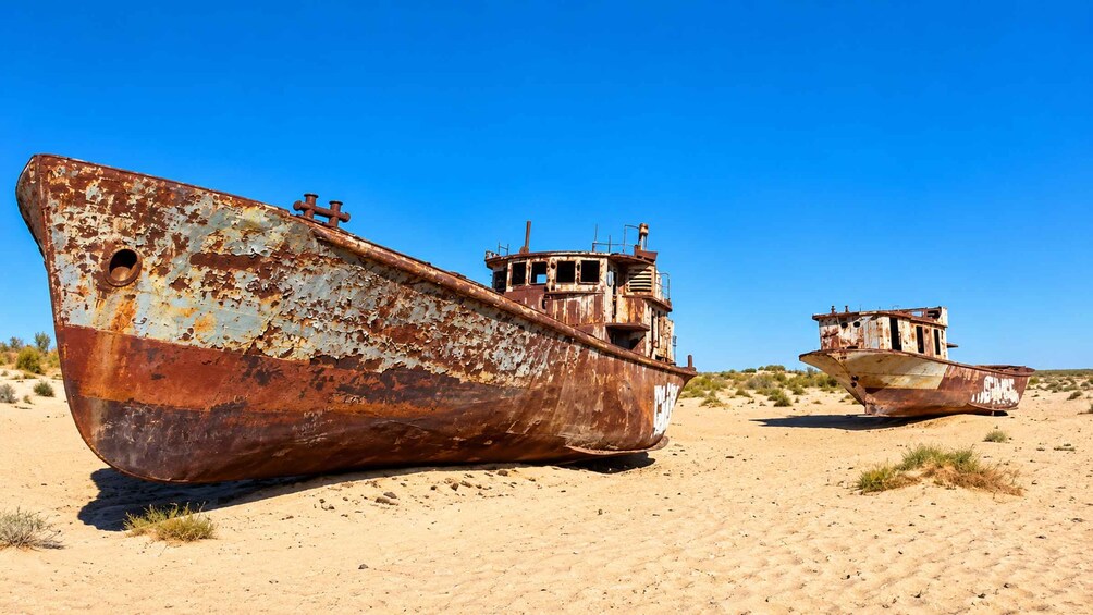 Two rusted boats in a desert landscape. 3