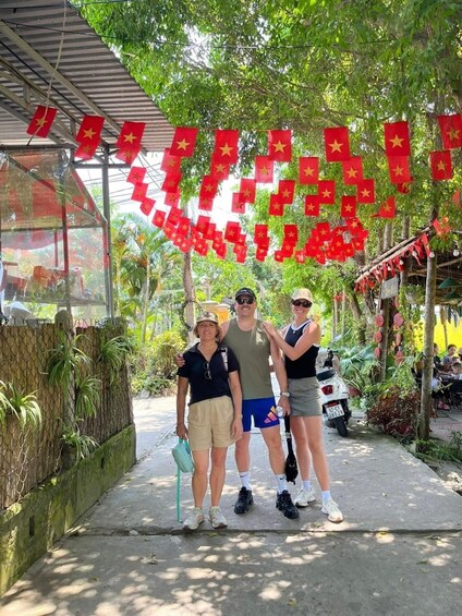A group of people standing under a canopy with red flags. 3