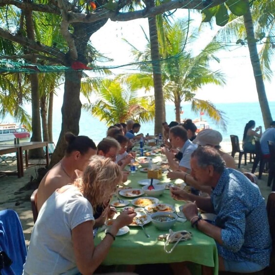 A group of people dining at a beachside table with a view of the ocean. 5