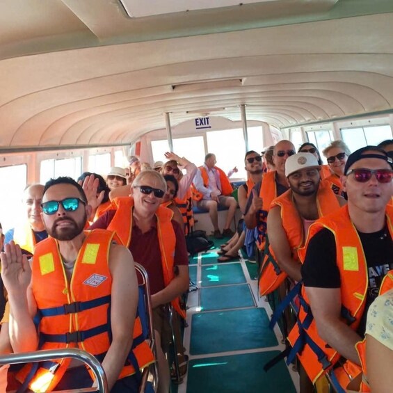 People on a boat wearing orange life jackets. 2