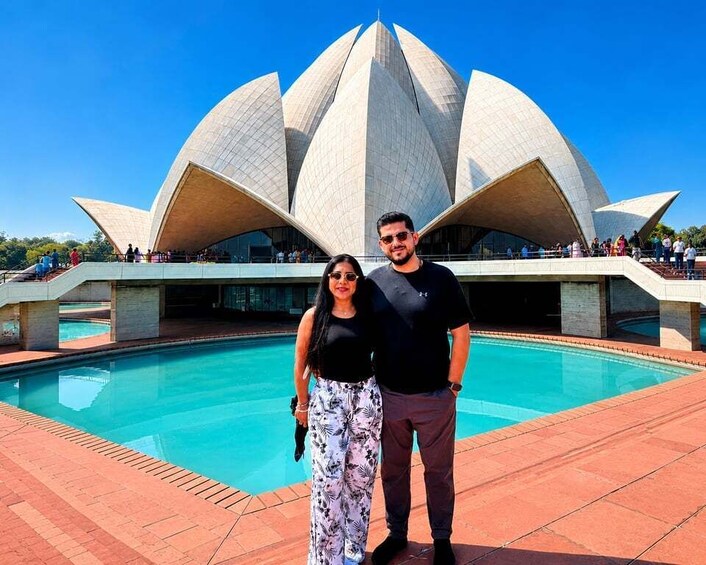 A couple standing in front of a lotus-shaped building with a pool. 1