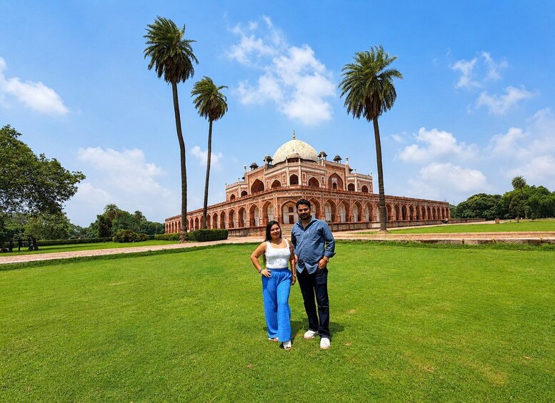 A large, historic building with a dome and arched windows, surrounded by a well-maintained lawn and palm trees. 5