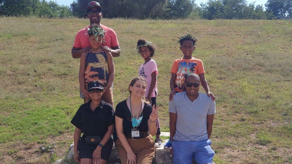 A group of people posing in a grassy field with trees in the background. 5