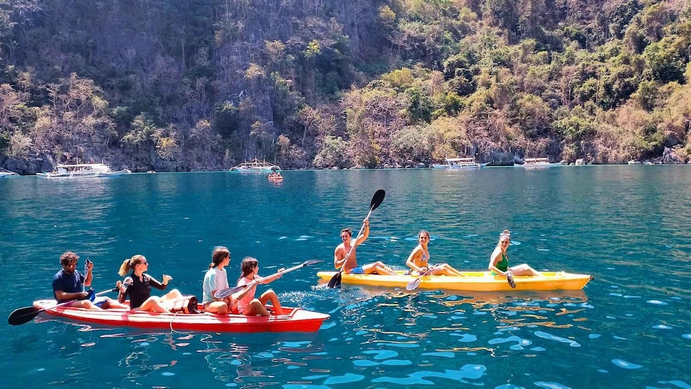 People kayaking on a calm lake surrounded by cliffs. 1