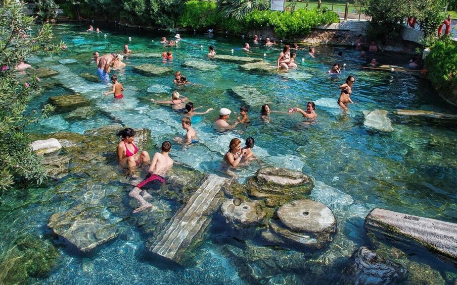A natural swimming pool with clear water, surrounded by rocks and greenery. 4