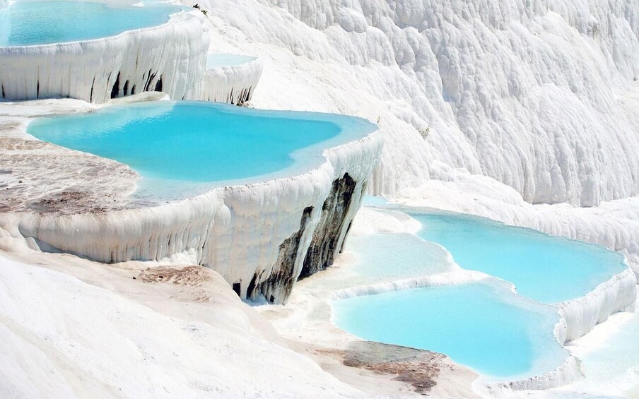 Terraced pools of turquoise water surrounded by white travertine formations. 2
