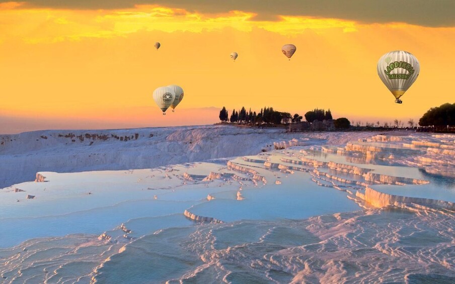 Terraced pools of mineral-rich water, a sunset sky, and hot air balloons. 5