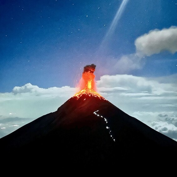 A volcano erupting at night with lava flowing down its side. 4