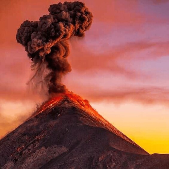 A volcano with a plume of smoke and ash rising from its peak. 3