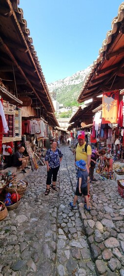 A cobblestone street with shops on either side, displaying various items for sale. 4