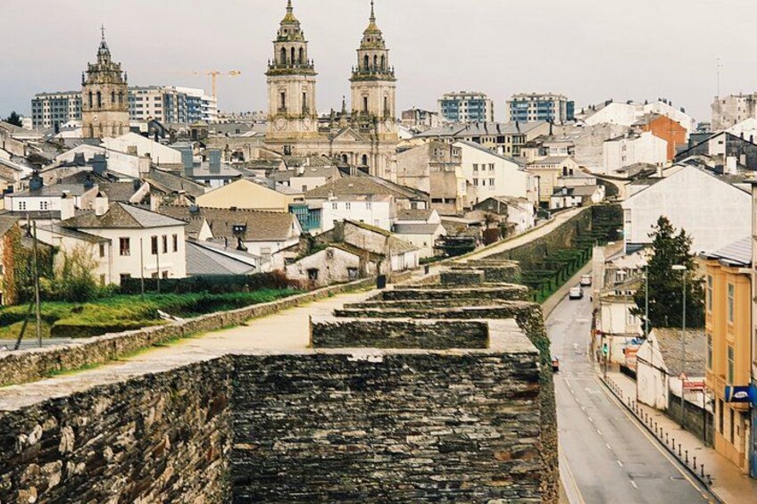 Eine Stadtansicht mit historischen Gebäuden, einer markanten Kirche und einer Steinmauer. 2