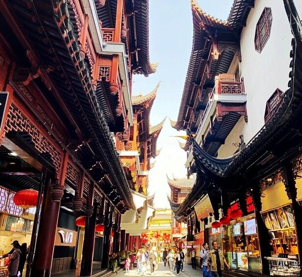 A traditional street with ornate buildings, red lanterns, and a crowd of people. 3