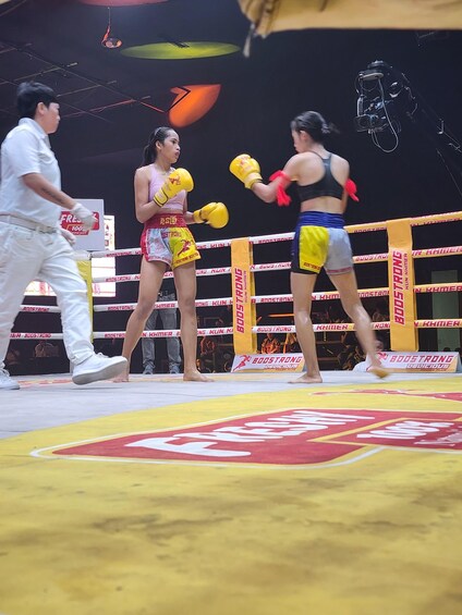 A boxing ring with two female boxers and a referee. 2