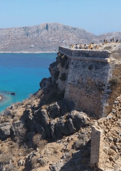 A coastal cliff with ruins and a clear blue sea. 2