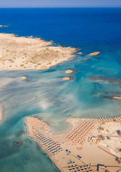 An aerial view of a coastal area with clear blue waters, sandy beaches, and numerous umbrellas. 1