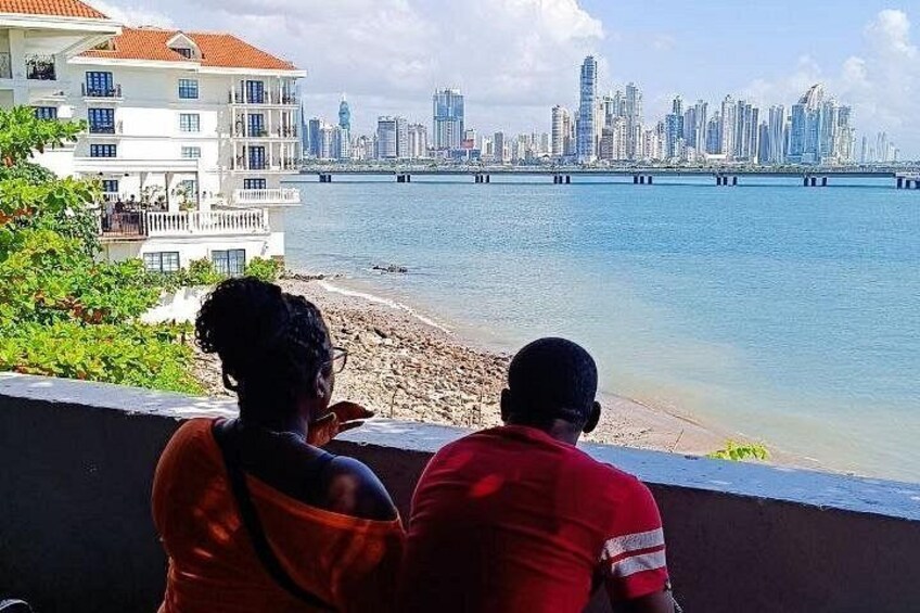 Two people overlooking a beach with a city skyline in the background. 3