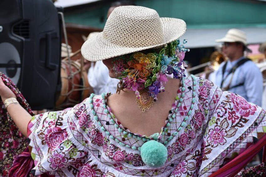 Eine Person in einem traditionellen bestickten Kleid mit einem blumenbesetzten Hut. 4