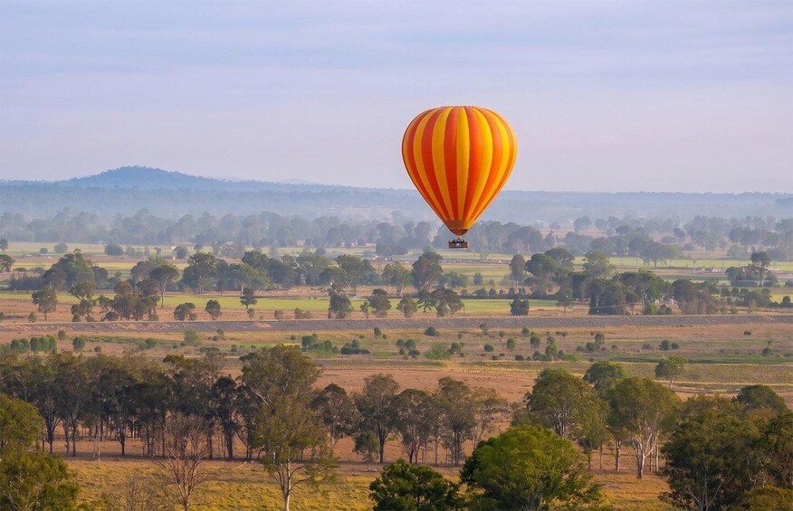 A hot air balloon over a rural landscape with fields and trees. 5