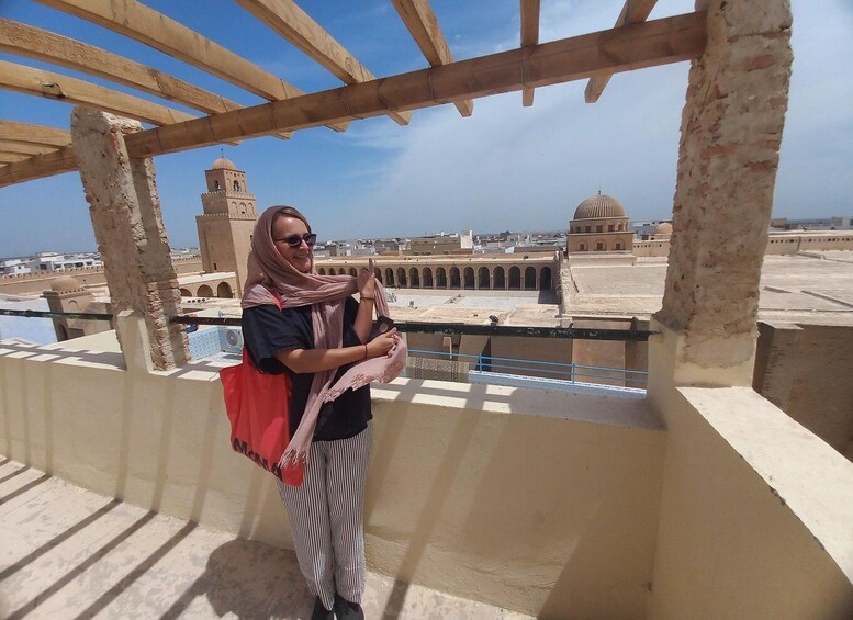 A person standing on a balcony with a view of historical buildings and a dome in the background. 2