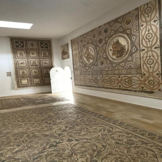 A room with patterned carpets, a large tapestry, and framed artwork on the walls. 5
