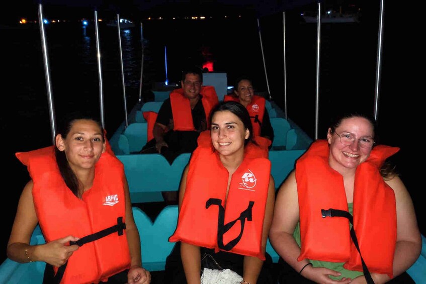 People on a boat wearing orange life jackets. 5