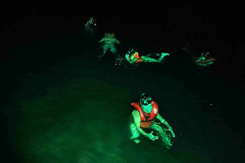 Two people swimming in a dark, greenish water body. 3