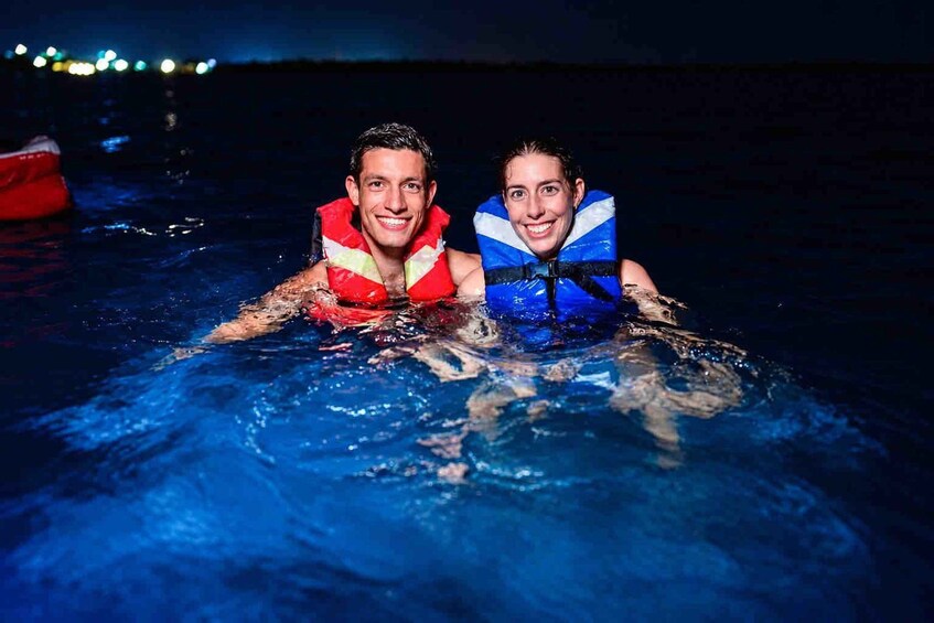 Two people in a swimming pool wearing life jackets. 1