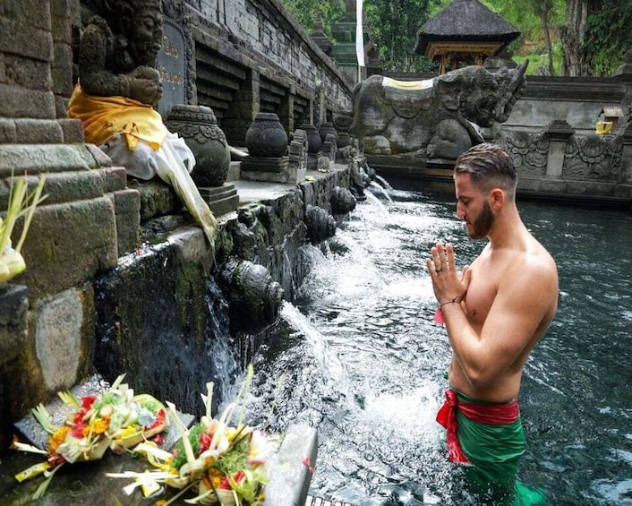 Un hombre orando en un templo con una fuente de agua y ofrendas. 2