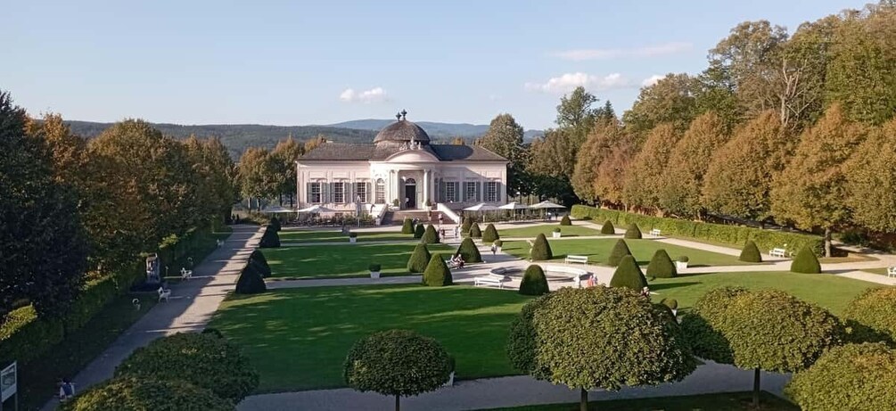 A large, white building with a dome, surrounded by a well-manicured garden with neatly trimmed hedges and a clear pathway leading to the entrance. 5