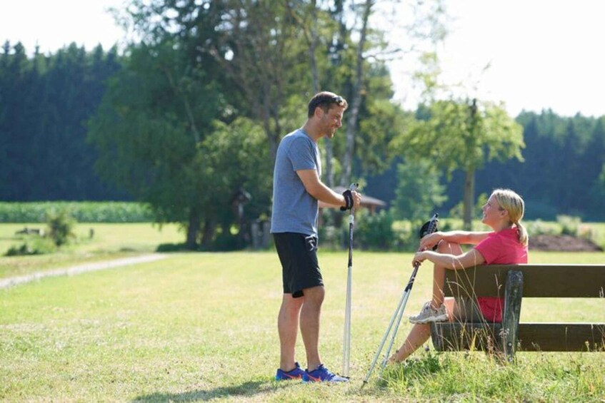 A man with a walking stick and a woman sitting on a bench in a park. 3