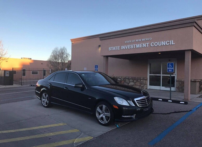 A black Mercedes-Benz parked in front of the State Investment Council building in New Mexico. 1