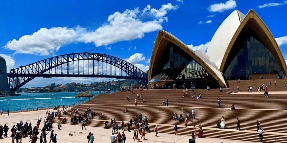 The Sydney Opera House and the Sydney Harbour Bridge with people walking around. 1