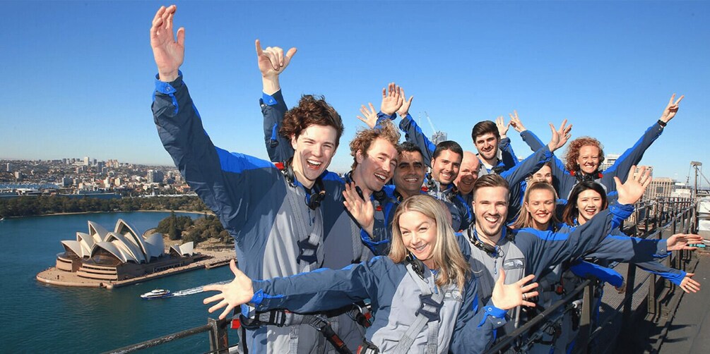 A group of people in blue jackets on a bridge with the Sydney Opera House in the background. 5