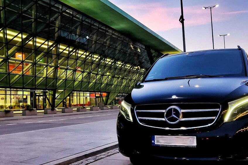 A black Mercedes-Benz SUV parked in front of a modern glass building with a green roof. 5