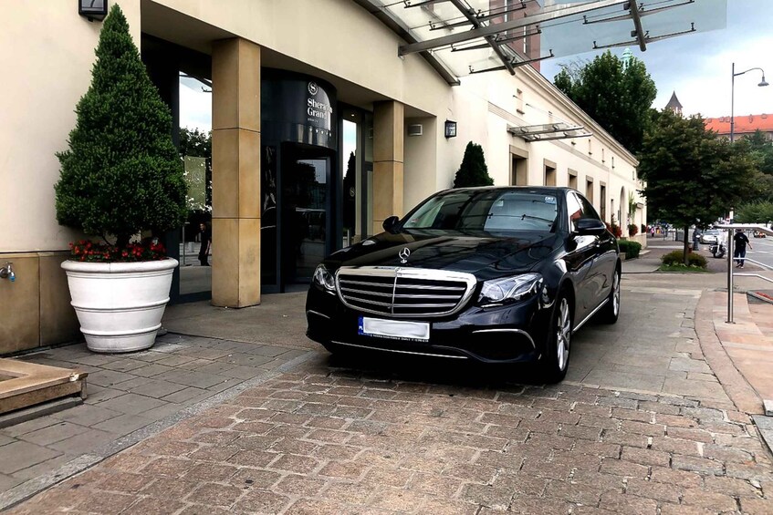 A black Mercedes-Benz parked in front of a building with a sign that reads "Sheraton Grand." 3