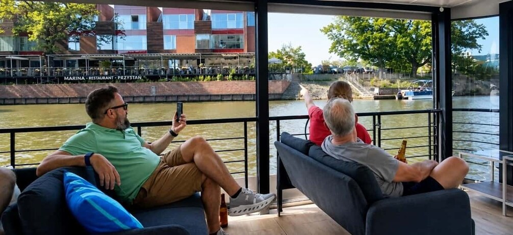 People relaxing on a boat with a view of a river and buildings in the background. 5
