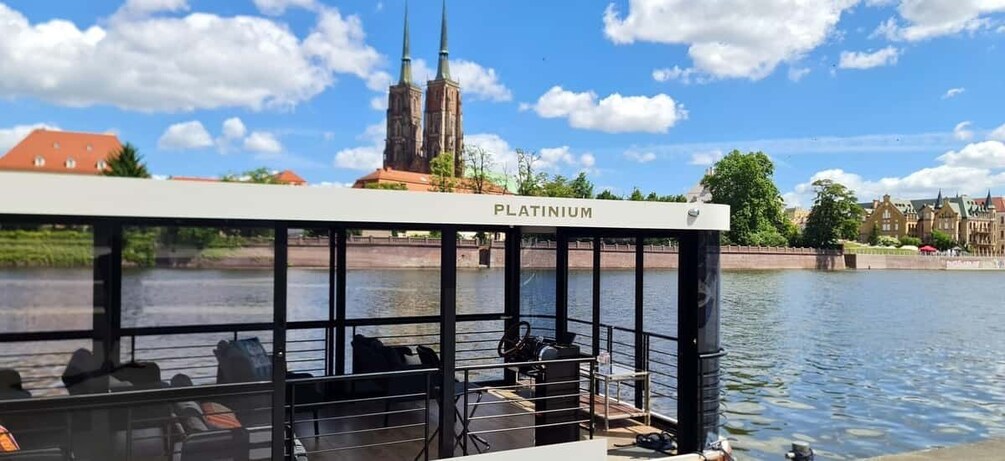 A boat named 'PLATINIUM' on a river with a church in the background. 4