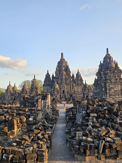 Ancient stone ruins with multiple structures, a central pathway, and a clear sky. 2