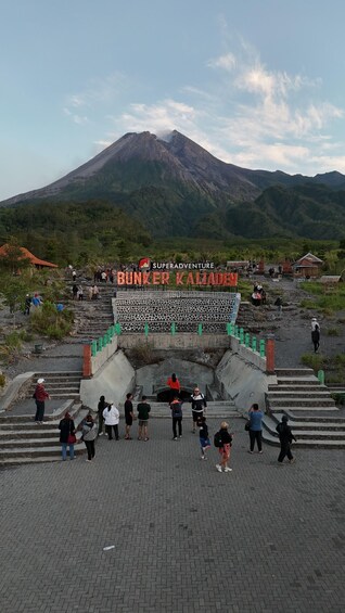 A group of people at the entrance of Bunker Kaladen, with a mountain in the background. 3