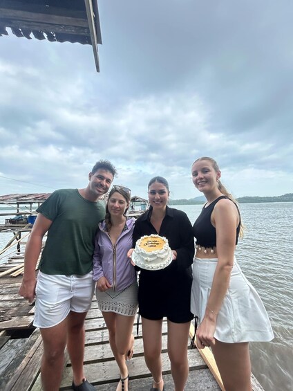 Four people on a wooden dock by a lake with a cloudy sky. 5