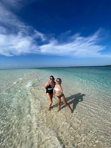 Two people standing in shallow clear water with a clear sky. 3