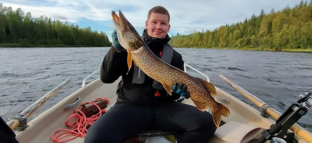 A person holding a large fish on a boat. 1