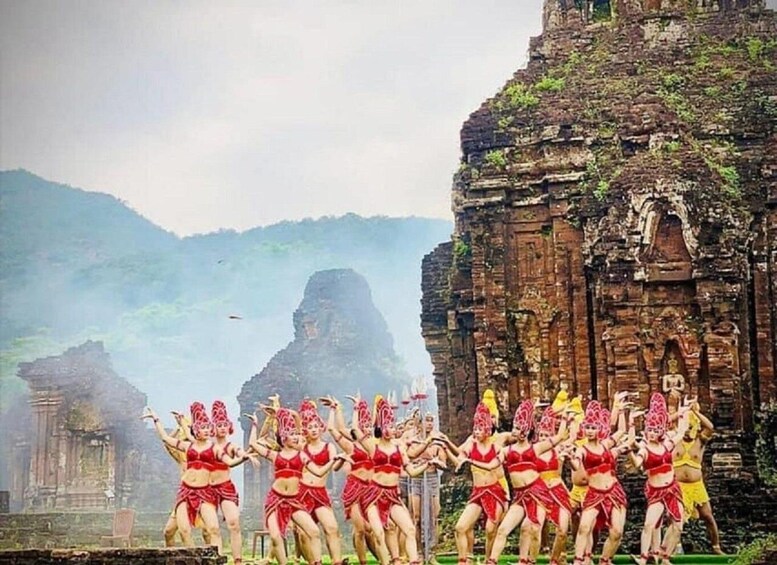 A group of dancers performing in front of ancient ruins. 3