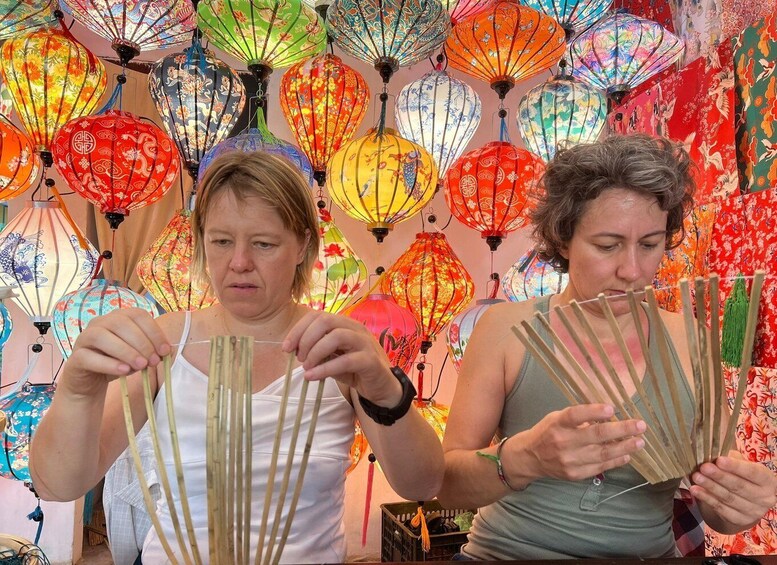 Two individuals crafting traditional lanterns with bamboo sticks. 2